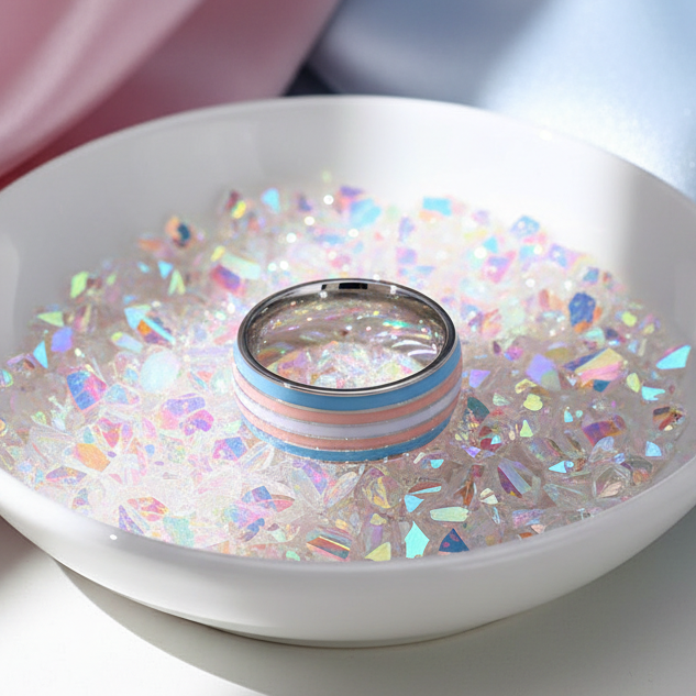 Transgender Pride Ring with light blue, pale pink, and white stripes on a stainless steel band, nestled in iridescent confetti. Celebrating LGBTQIA+ pride and self-expression with bold, joyful queer energy.