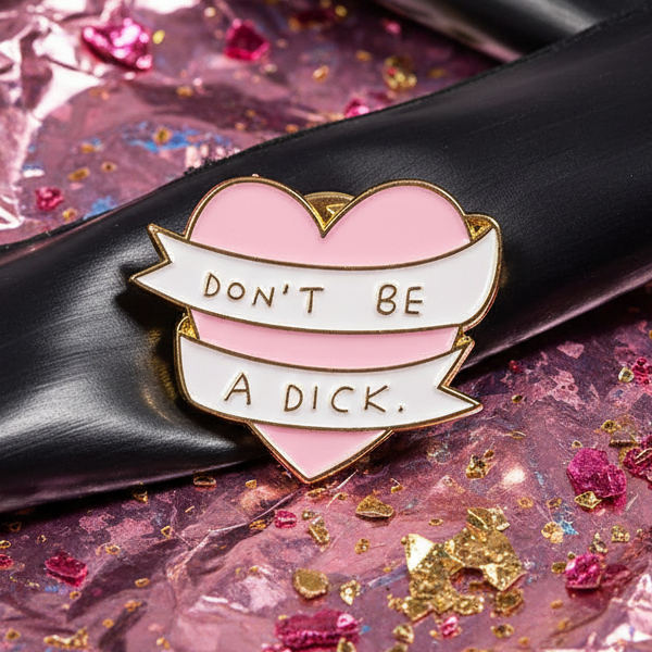 “DON’T BE A DICK” enamel pin with a pink heart and white banner