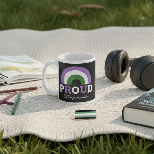 Black mug reading “PROUD” and “Of being aromantic,” with aromantic stripes outdoors