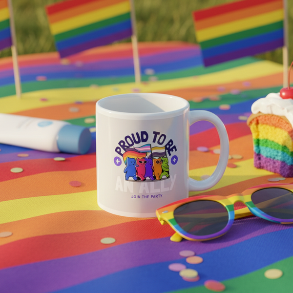 White mug reading “PROUD TO BE AN ALLY” on a rainbow-striped party table