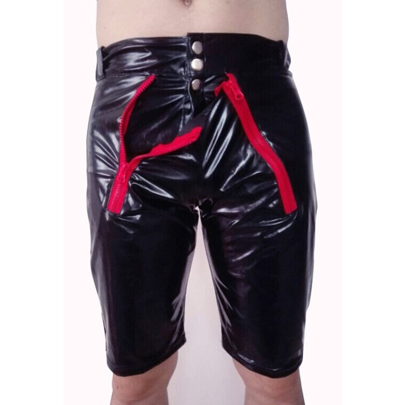 Front view of a model wearing glossy black faux-leather shorts with red zippers and snaps