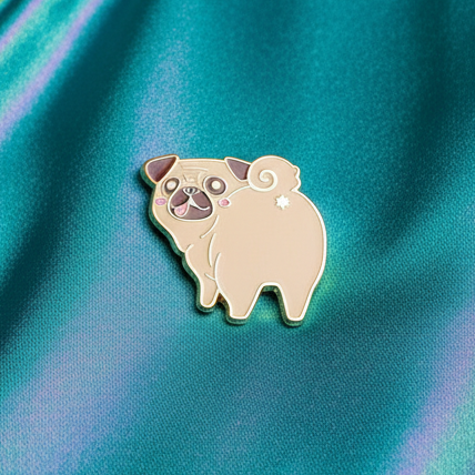 Close-up of a pug butt enamel pin on shimmering teal and purple fabric