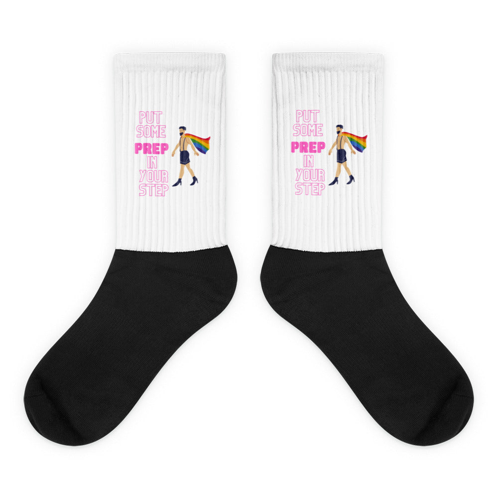 Pair of black-and-white socks with pink “PUT SOME PREP IN YOUR STEP” text and rainbow-caped figure