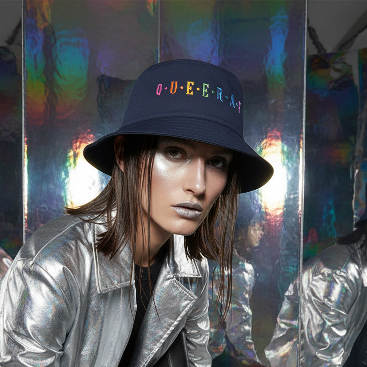 Queer AF Bucket Hat with "QUEERAF" in rainbow thread, rocked by a silver-jacketed