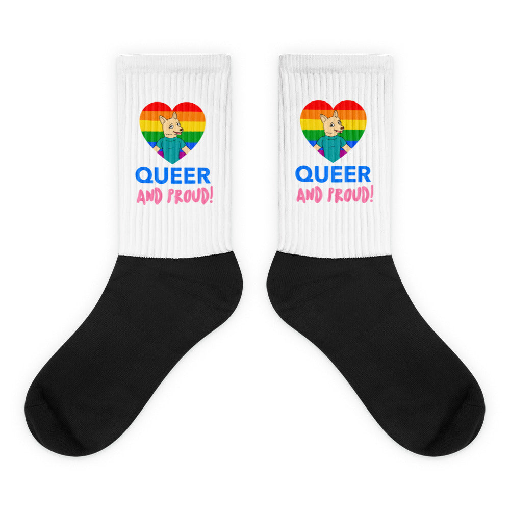 Pair of crew socks with black feet and white cuffs reading “QUEER AND PROUD!”