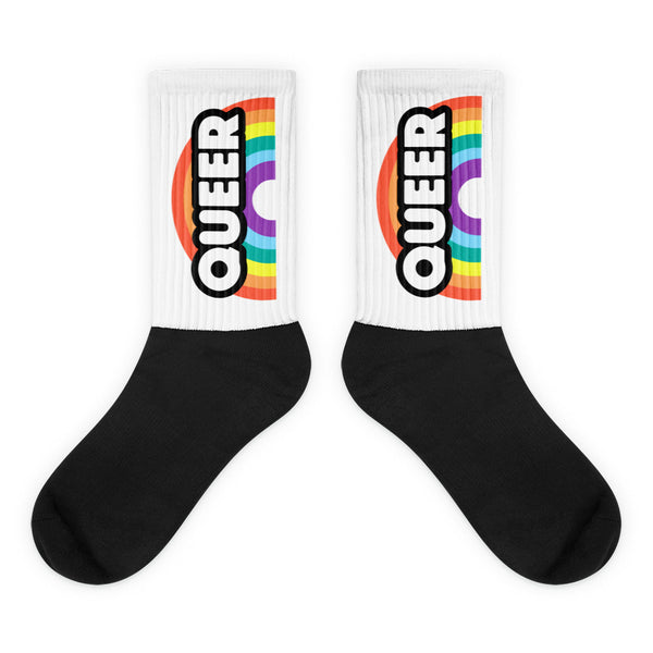 Pair of black-and-white crew socks with rainbow stripes and vertical “QUEER” lettering