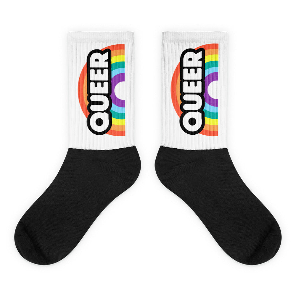Pair of black-and-white crew socks with rainbow stripes and vertical “QUEER” lettering