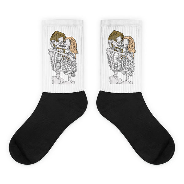 Pair of black crew socks with white cuffs showing two skeletons kissing