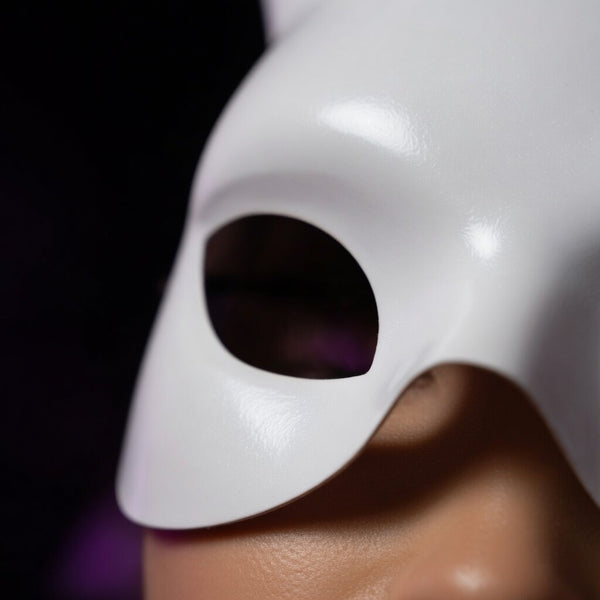 Close-up side view of a glossy white rabbit-style mask with a large eye opening
