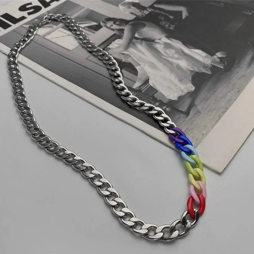 Silver chain necklace with a short section of rainbow-colored acrylic links, photographed on a magazine