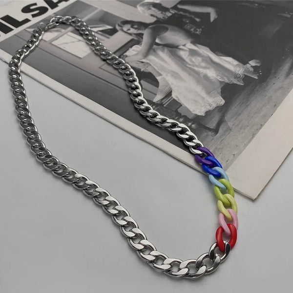 Silver chain necklace with a short section of rainbow-colored acrylic links, photographed on a magazine