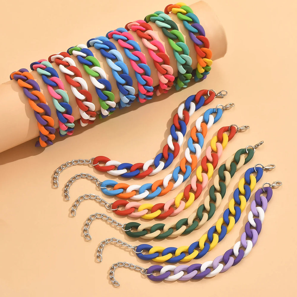 Colorful chunky chain-link bracelets arranged on an arm and peach background