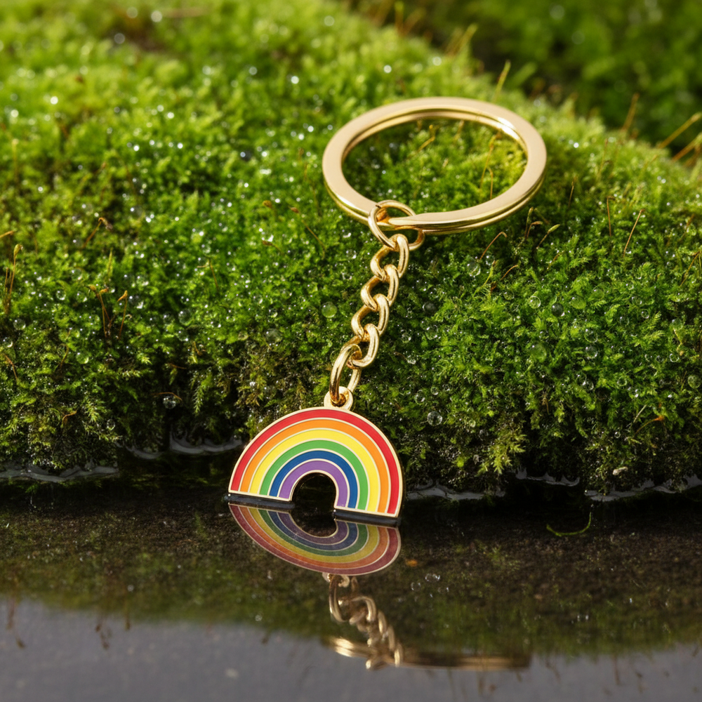 Rainbow enamel keychain with gold-tone ring and chain on moss