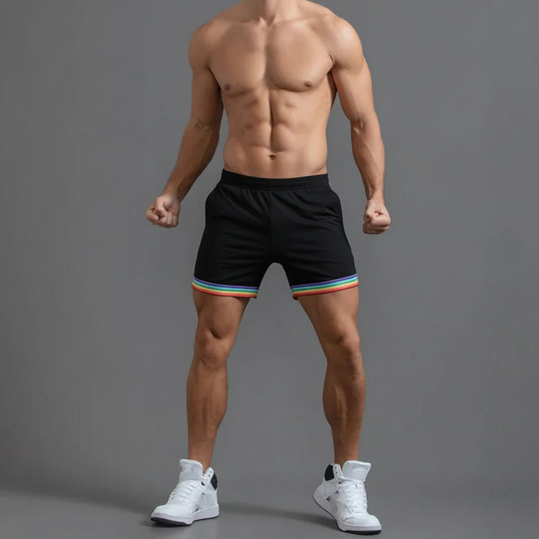 Front-facing shirtless model wearing black shorts with rainbow-striped hems