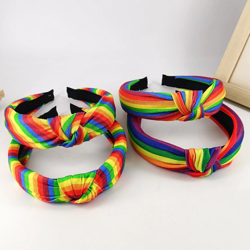 Three rainbow-striped fabric headbands with knotted fronts, shown on a white surface
