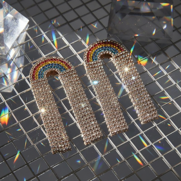 Rainbow rhinestone arch earrings on a reflective grid surface