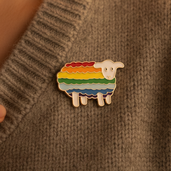 Rainbow-striped sheep enamel pin attached to a brown knitted sweater