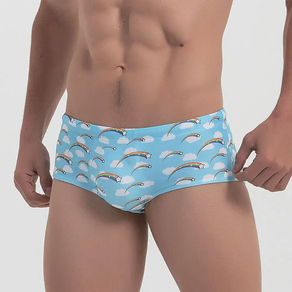 Sky-blue swim briefs patterned with rainbow arcs, white clouds, and stars