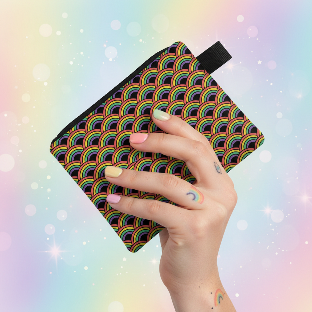 Hand holding a rainbow-patterned coin purse with a black wrist strap