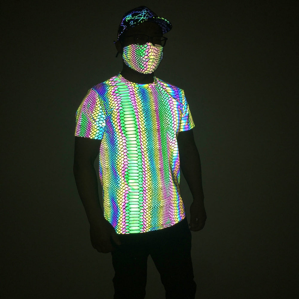 Front-facing model wearing a brightly reflective rainbow-patterned T-shirt in low light