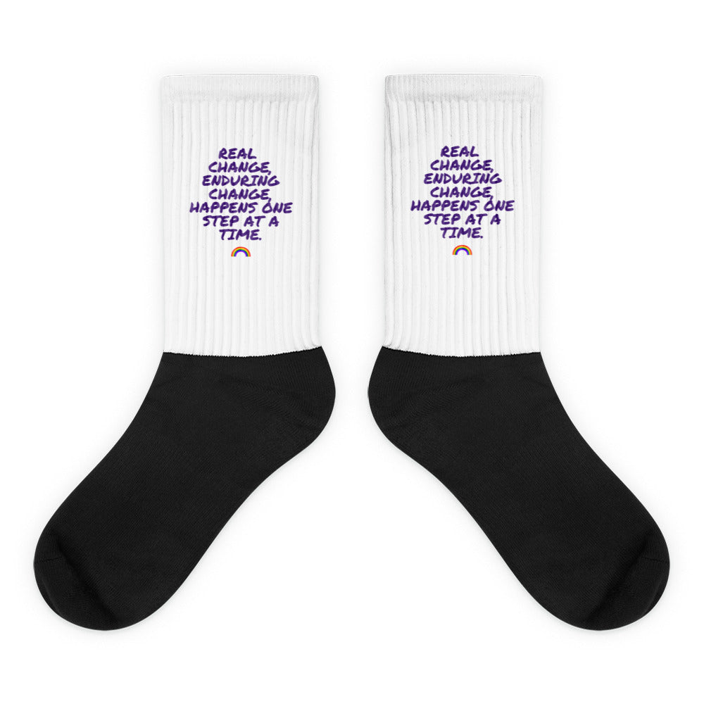 Pair of white ribbed-cuff socks with purple slogan, rainbow, and black feet
