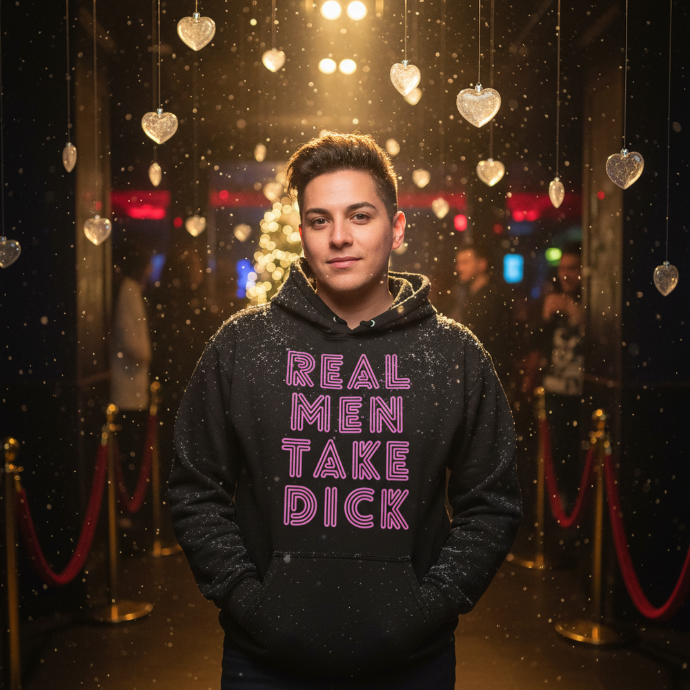 Person wearing a black hoodie reading “REAL MEN TAKE DICK” in pink lettering