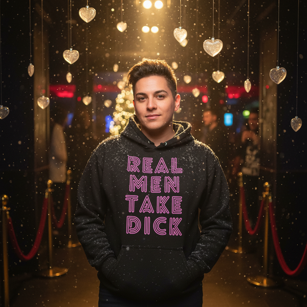 Person wearing a black hoodie reading “REAL MEN TAKE DICK” in pink lettering