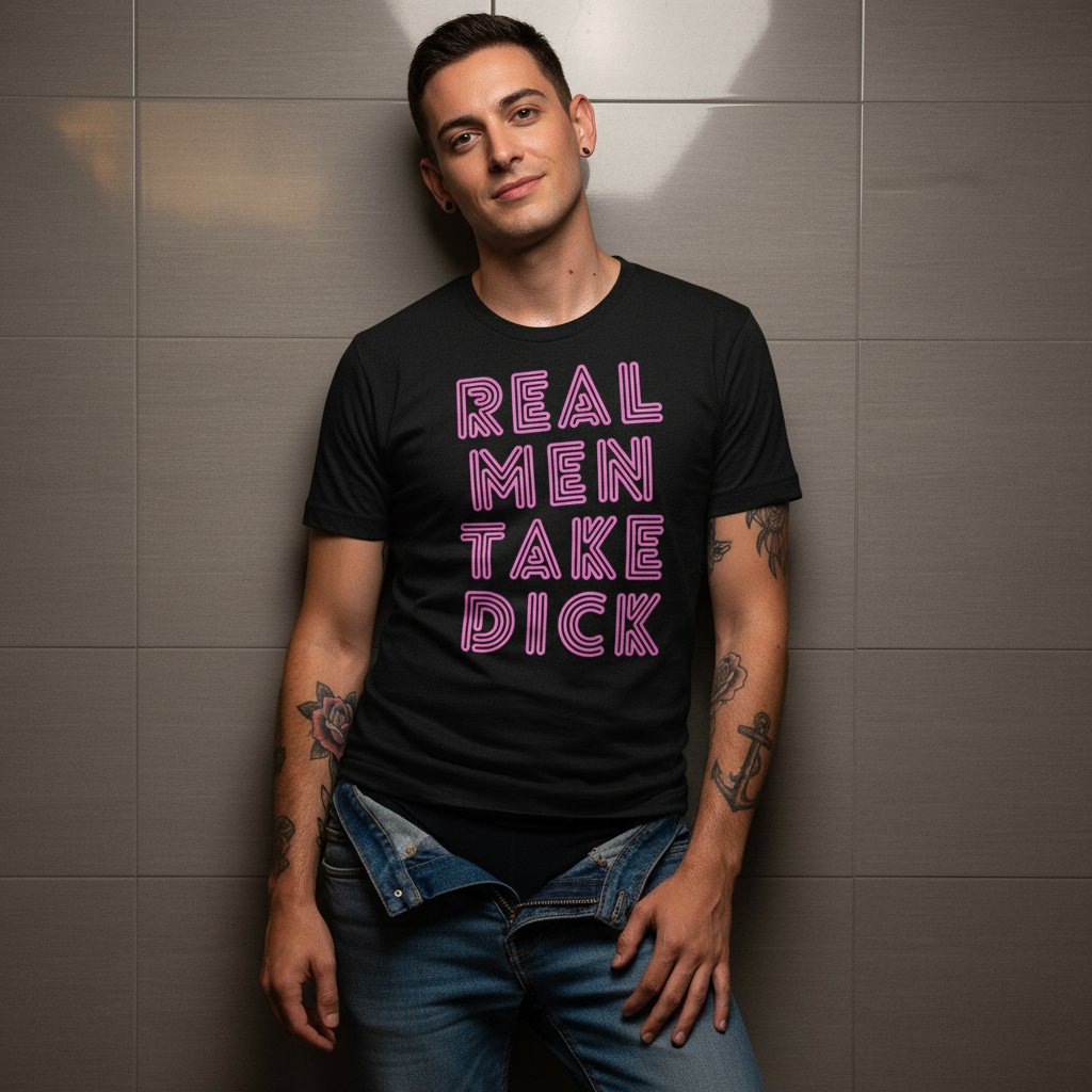 Front-facing person wearing a black T-shirt reading “REAL MEN TAKE DICK” in pink lettering