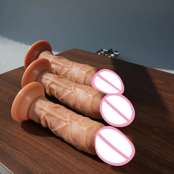 Three flesh-toned realistic dildos with flared suction-cup bases on a wooden table