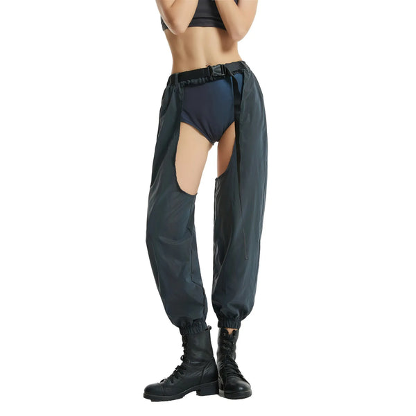 Front view of dark parachute pants with open sides, worn over black briefs and boots