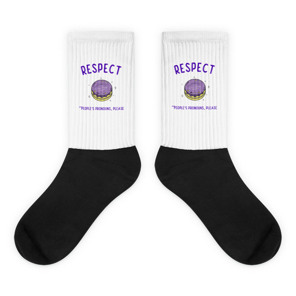 Pair of black-and-white socks with purple “RESPECT” and “PEOPLE’S PRONOUNS, PLEASE” text