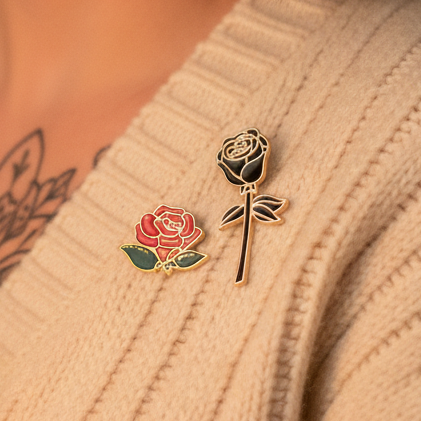 Red and black rose enamel pins attached to a beige knitted garment