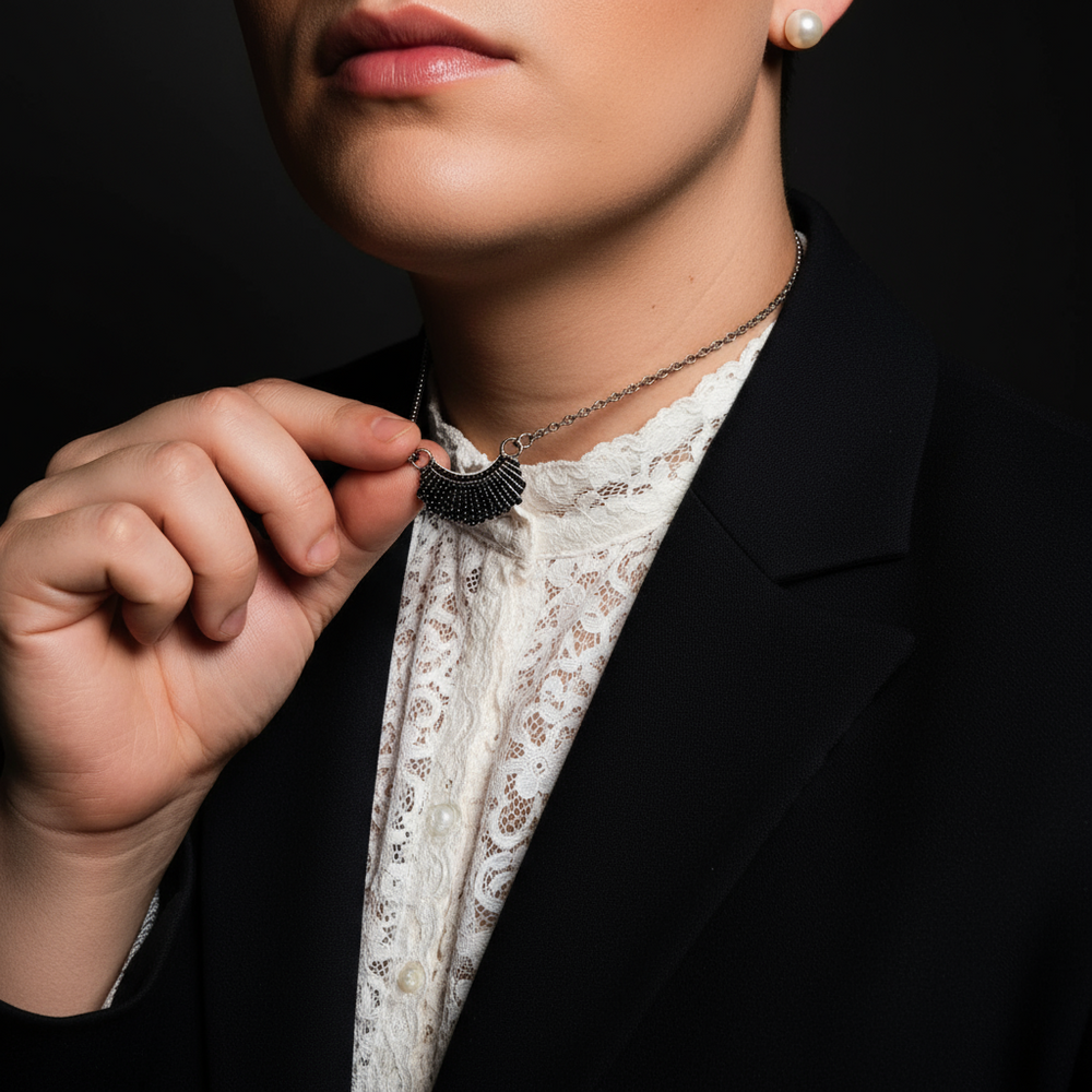 Close-up of a person holding a black fan-shaped Ruth Bader Ginsburg pendant necklace