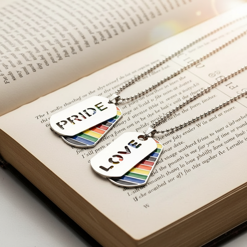 Two ball-chain dog-tag necklaces reading “PRIDE” and “LOVE” on an open book