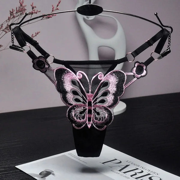 Black adjustable thong with pink-and-black butterfly embroidery, displayed on a hanger