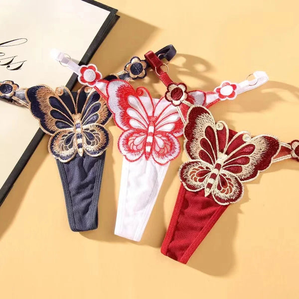 Flat lay of three adjustable butterfly-embroidered thongs in navy, white, and red