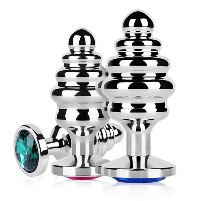 Three reflective ribbed stainless steel butt plugs with blue, pink, and teal jewel bases