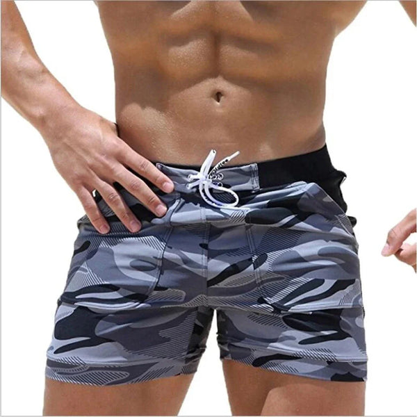Model wearing gray and black camouflage board shorts with a white drawstring