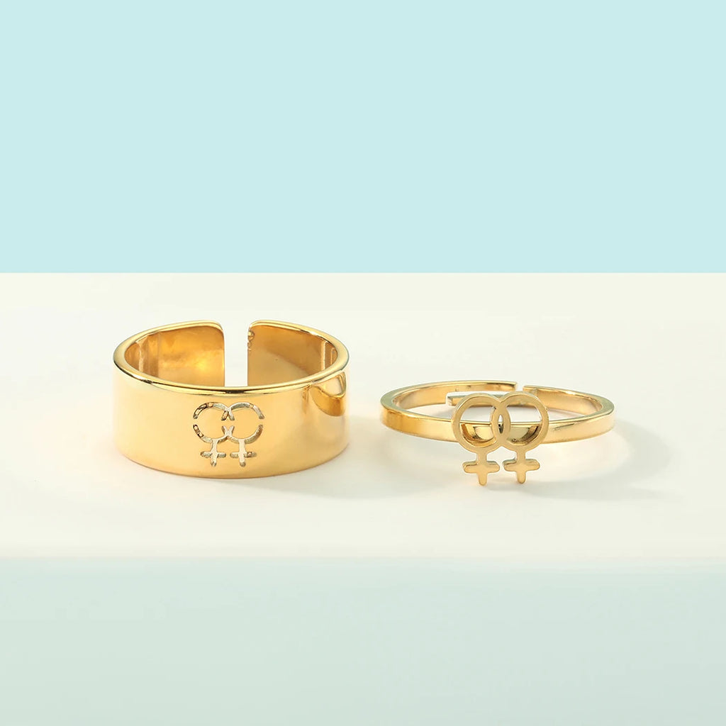 Gold lesbian symbol rings, including a wide band and an open double-female-symbol ring