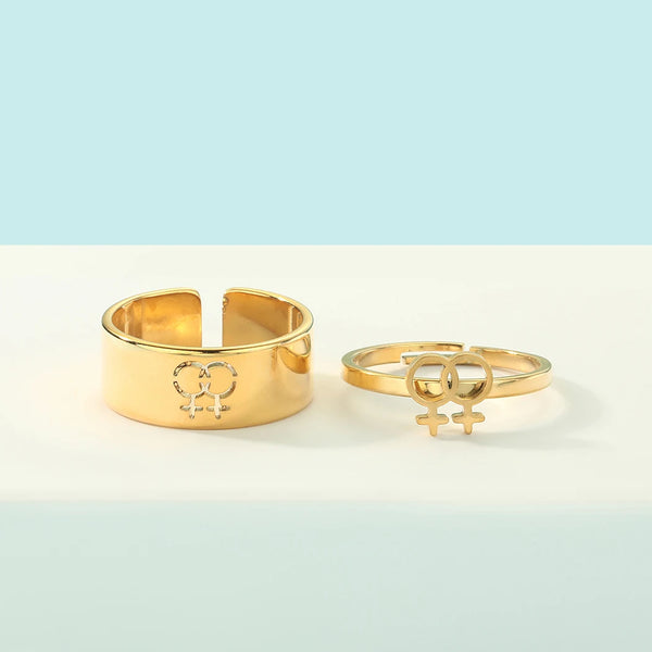 Gold lesbian symbol rings, including a wide band and an open double-female-symbol ring