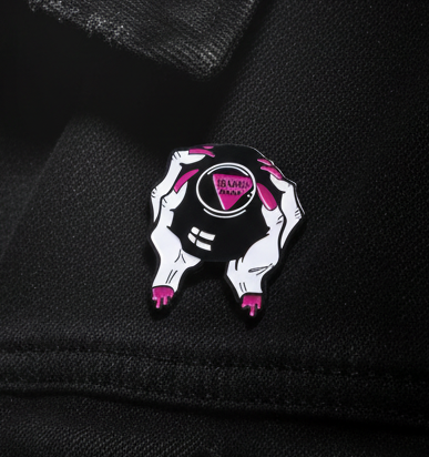 Sashay Away Enamel Pin on black jacket: Two white hands with hot-pink drips hold a black orb