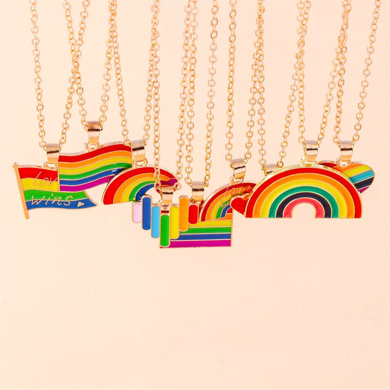 Collection of rainbow pendant necklaces in multiple colours, arranged on a pale peach background
