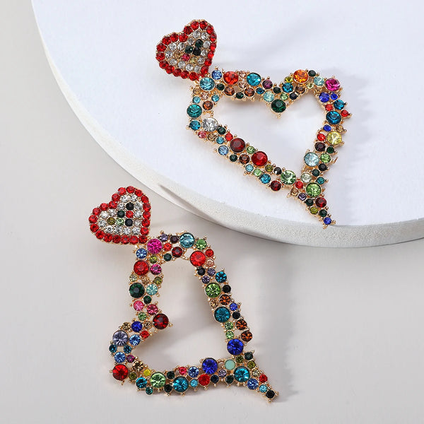 Heart-shaped rhinestone earrings with multicolored crystal accents on a white display