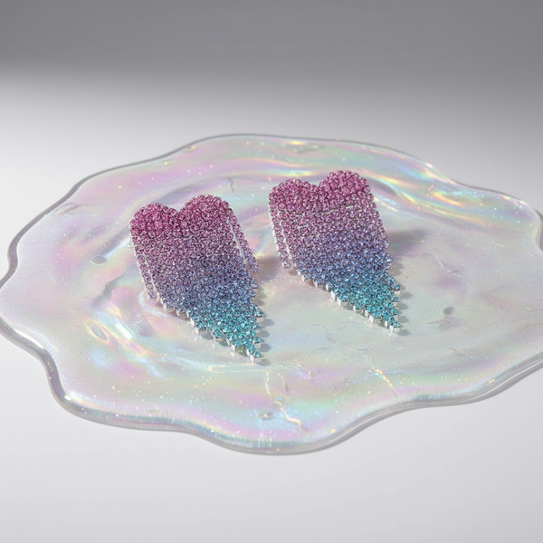 Pink and blue rhinestone heart earrings on an iridescent dish