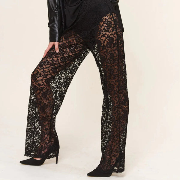 Close-up model view of black floral lace trousers with wide flared legs