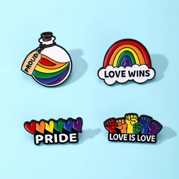 Four rainbow Pride enamel pins reading “PROUD,” “LOVE WINS,” “PRIDE,” and “LOVE IS LOVE”