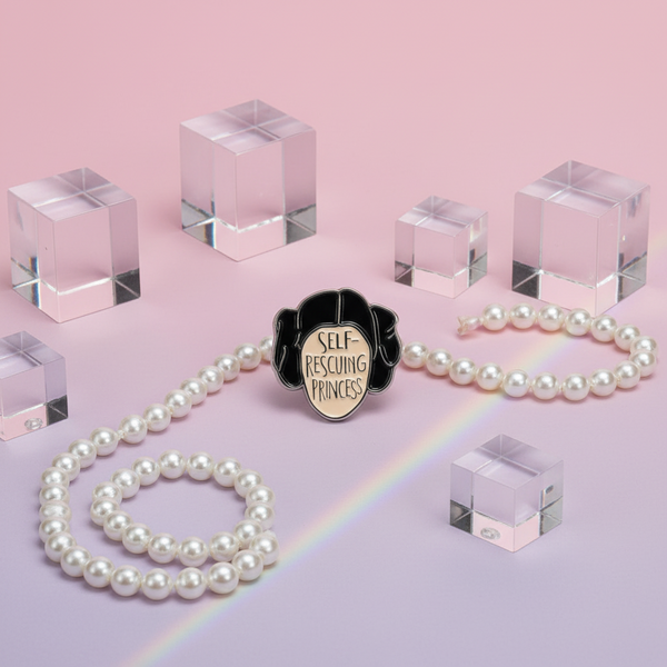 Self-Rescuing Princess enamel pin with black hair silhouette and readable text on a pearl necklace