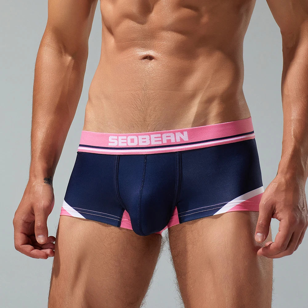Front view of a model wearing navy pouch boxer briefs with pink trim