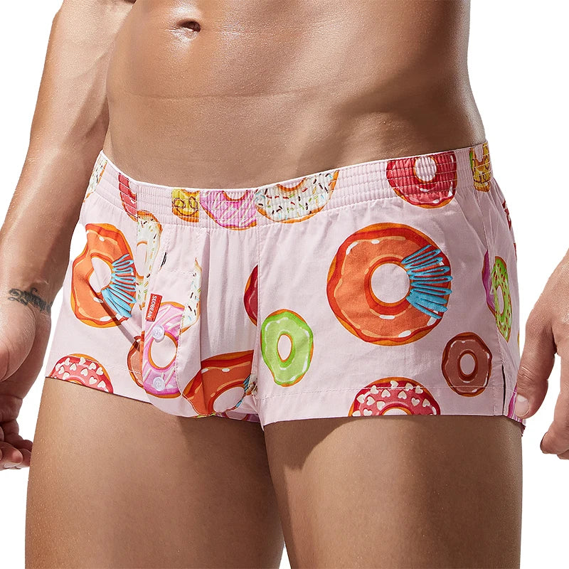 Cropped model wearing pink boxer briefs covered in colorful donut illustrations