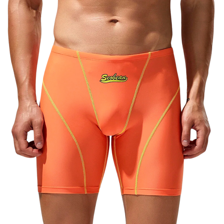 Front view of a model wearing bright orange swim boxers with yellow seam accents and logo